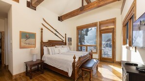 A bedroom with a wooden four-poster bed, a wooden bench, a nightstand, and a window with a view of a snowy landscape. - Retreat at Union Creek II:  Easy Walk to Lift, Hot Tub, Foosball, Shuttle (Copper Mountain)