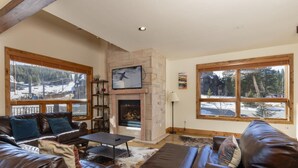 A cozy living room with leather sofas, a fireplace, and large windows offering a snowy mountain view. - Retreat at Union Creek II:  Easy Walk to Lift, Hot Tub, Foosball, Shuttle (Copper Mountain)