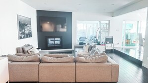 A modern living room with a large sectional sofa, a flat-screen TV, and a fireplace. - Modern 5bdr House with hot tub 7 min from Universal studios (north hollywood)