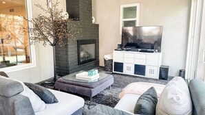A modern living room with a fireplace, a flat-screen TV, and a white entertainment unit. - Modern 5bdr House with hot tub 7 min from Universal studios (north hollywood)