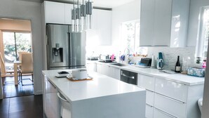 A modern kitchen with a large island, stainless steel appliances, and a view to the outside. - Modern 5bdr House with hot tub 7 min from Universal studios (north hollywood)