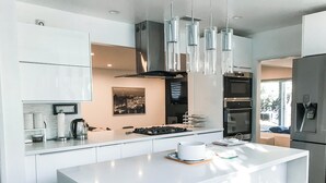 A modern kitchen with a central island, stainless steel appliances, and pendant lighting. - Modern 5bdr House with hot tub 7 min from Universal studios (north hollywood)