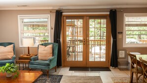 A living room with teal armchairs, a wooden coffee table, a dining table with chairs, and a sliding glass door leading to an outdoor deck. - Solitude in the Mountains (Flagstaff)
