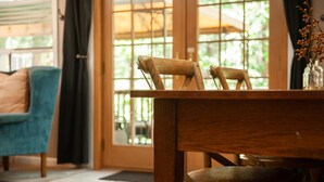 A wooden dining table with chairs, a teal armchair, and a vase with dried branches. - Solitude in the Mountains (Flagstaff)
