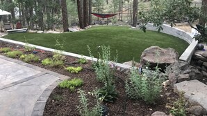 A landscaped garden with a well-maintained lawn, surrounded by trees and rocks. - Solitude in the Mountains (Flagstaff)