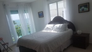Ett sovrum med en säng, ett nattduksbord, en stol och ett fönster med gardiner.