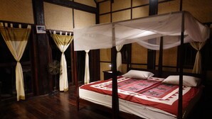 A four-poster bed with a canopy, a wooden floor, and a bedside table with a fan. - Nong Kiau Riverside (Nong Khiaw)