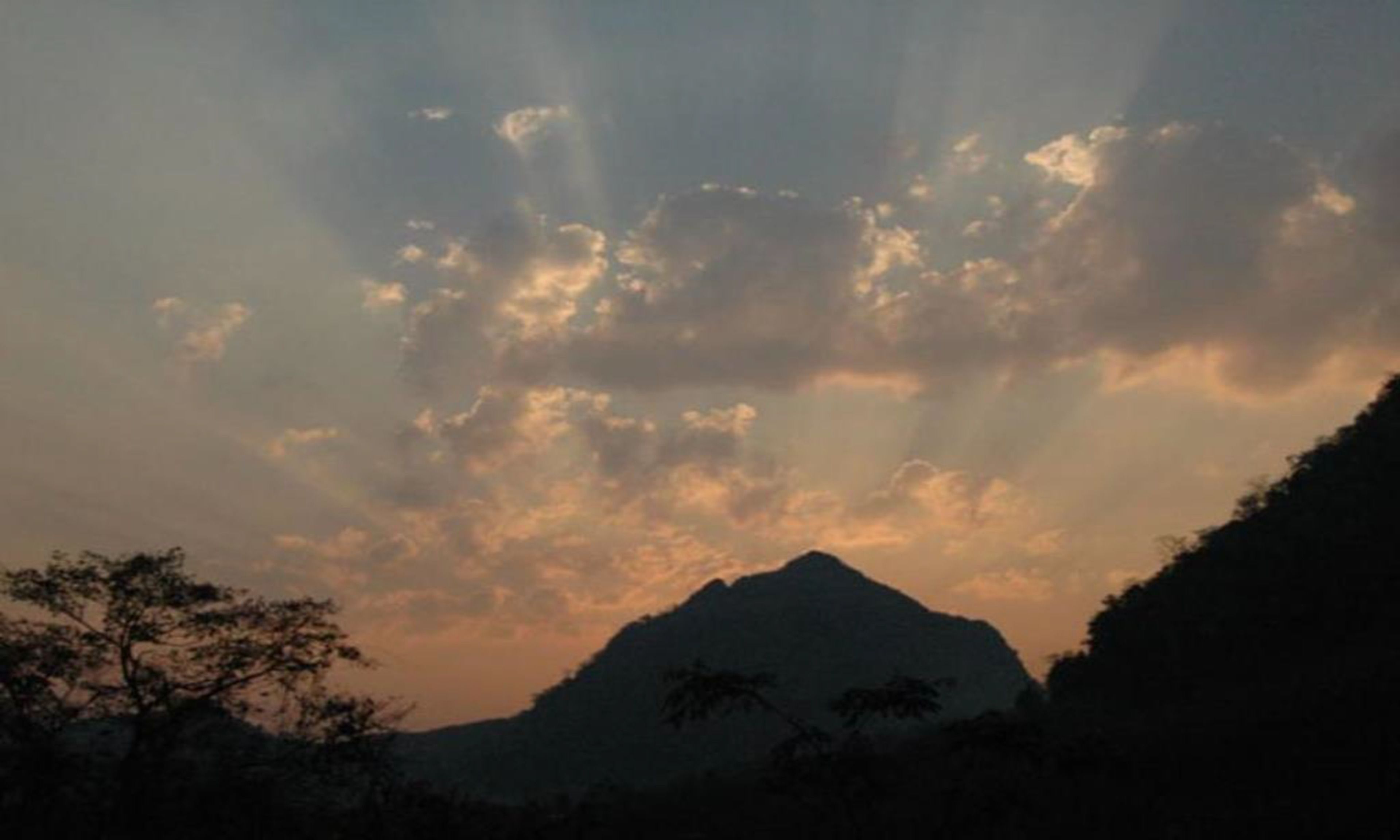 A mountain silhouette with a cloudy sky.