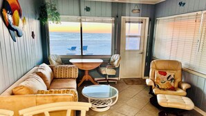 A cozy room with a sofa, chairs, a small table, and a view of the ocean.