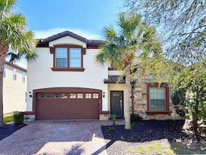 A two-story house with a brown garage door, a stone exterior, and a well-maintained driveway.