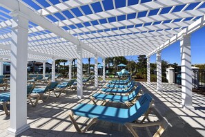 A covered outdoor seating area with blue cushioned chairs and a white pergola structure. - MEGA Mansion! Family Memories Made Here! Westside Resort Waterpark (Kissimmee)