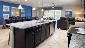 A modern kitchen with a central island, dark cabinetry, and pendant lighting. - MEGA Mansion! Family Memories Made Here! Westside Resort Waterpark (Kissimmee)