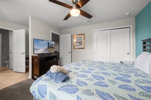 A bedroom with a bed, a television, a ceiling fan, and a door leading to another room. - No Rear Neighbors • Pool & Spa • Game Room • Lazy River • Gated Resort (Kissimmee)