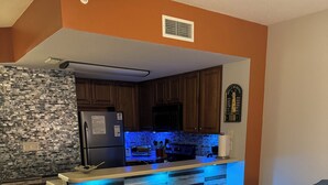 Una cocina moderna con una isla central, armarios de madera y un refrigerador de acero inoxidable.