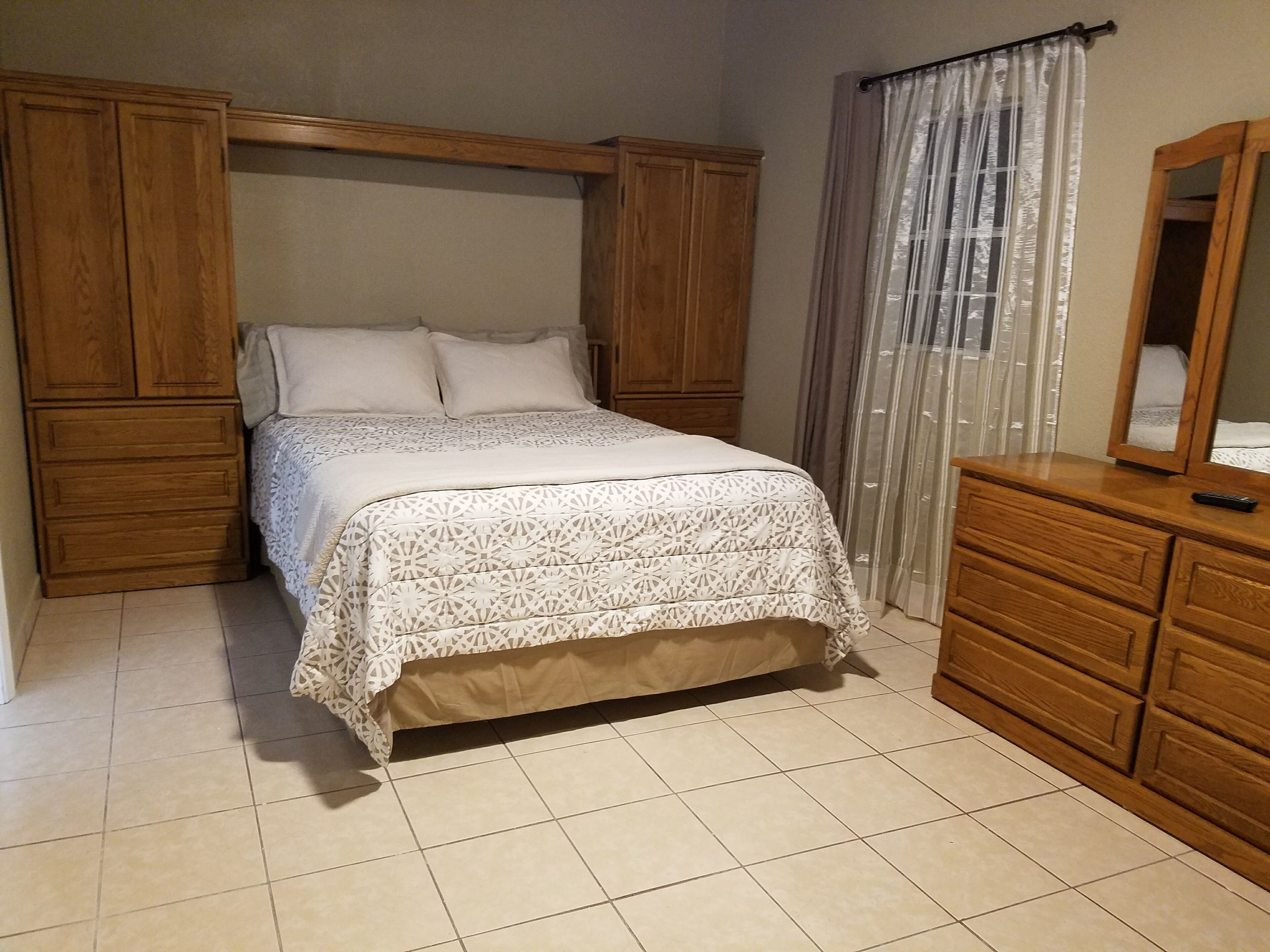 A bedroom with a bed, wooden wardrobe, and a dresser.