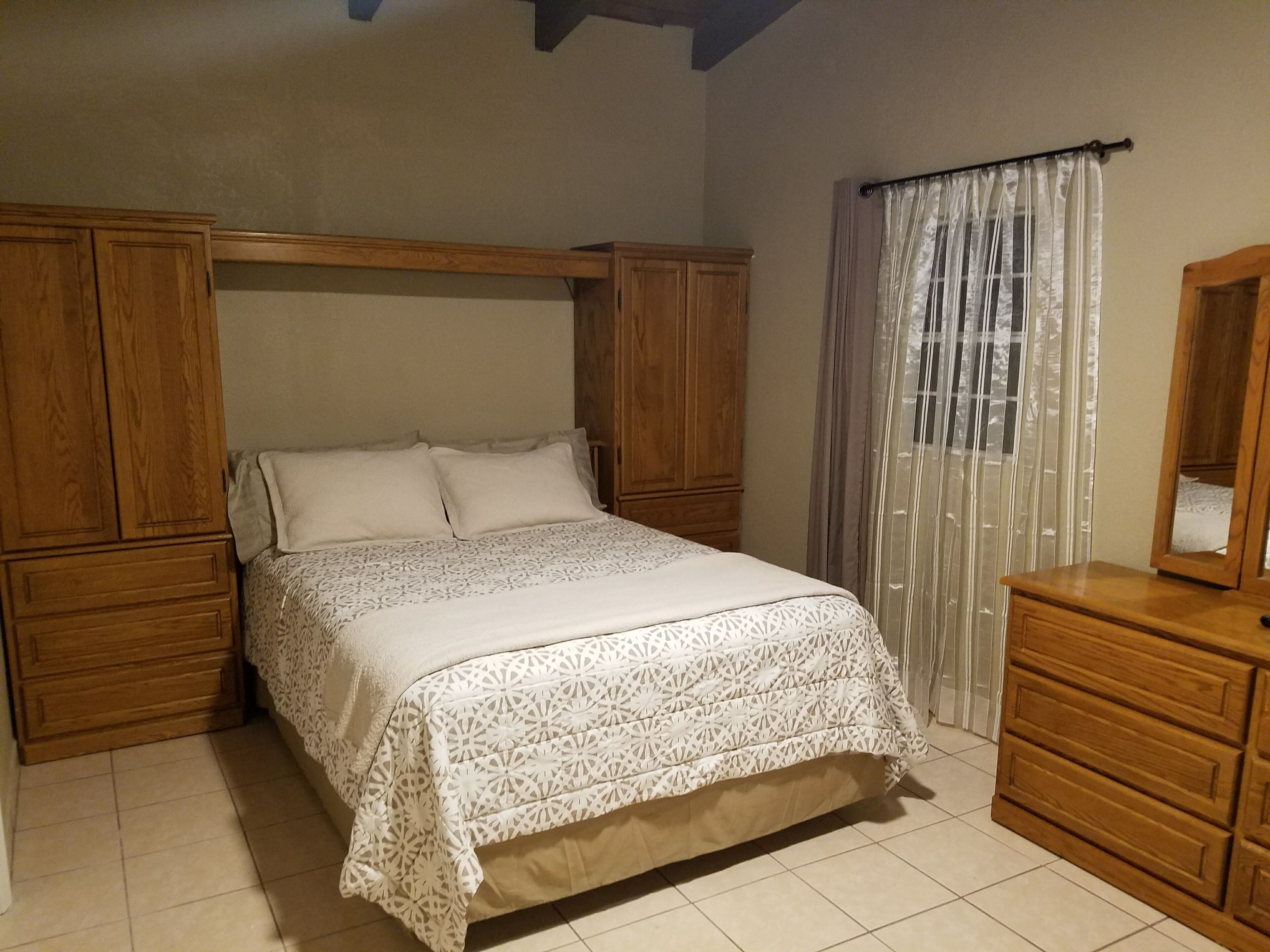 Ein Schlafzimmer mit einem Bett, einem Schrank aus Holz und einer Kommode.