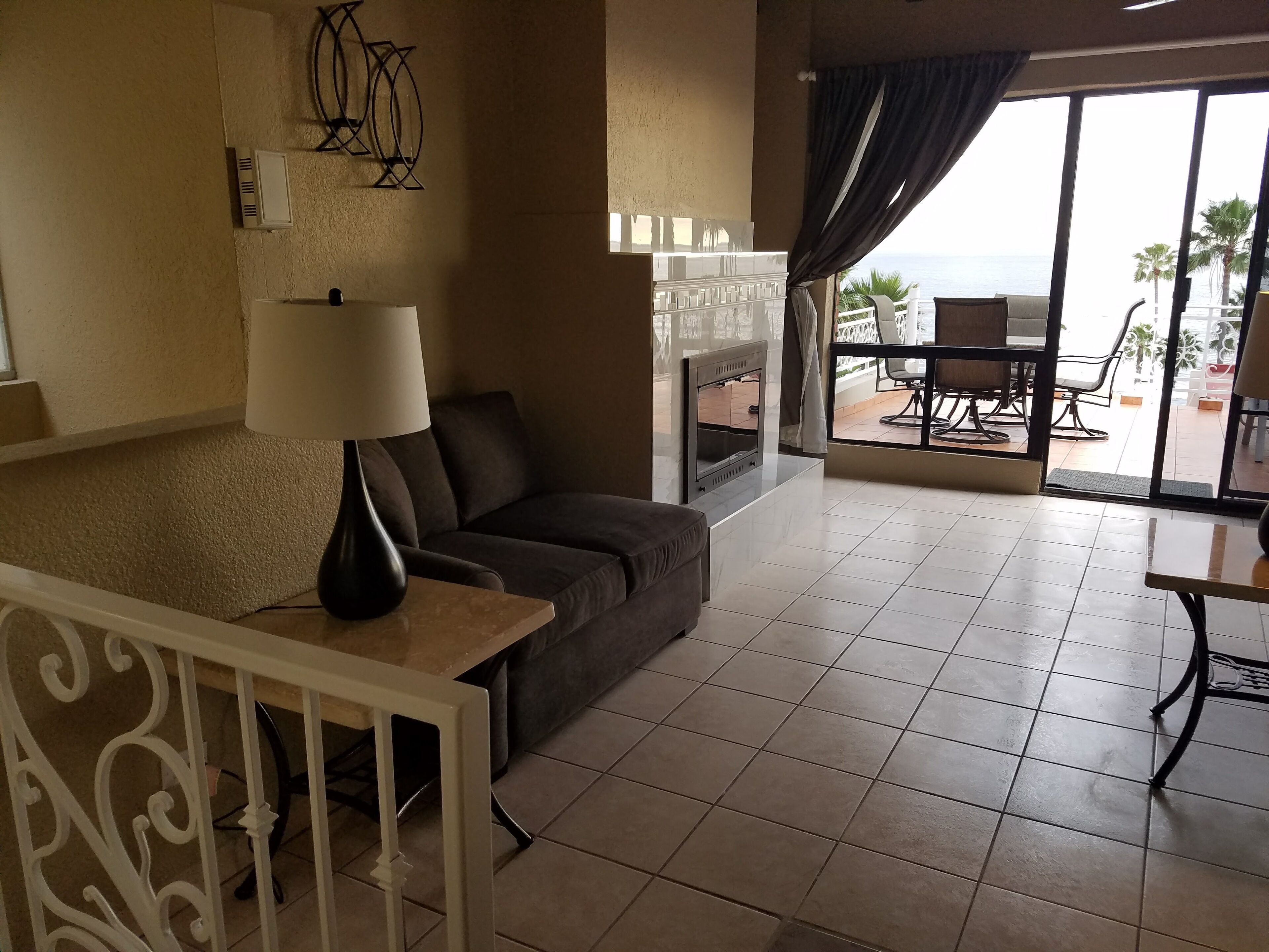 A living room with a sofa, a lamp, a TV, and a balcony with outdoor furniture.