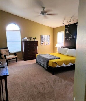 A bedroom with a bed, a chair, a dresser, a ceiling fan, and a window. - Quiet desert getaway, ping-pong, BBQ, citrus (Phoenix)