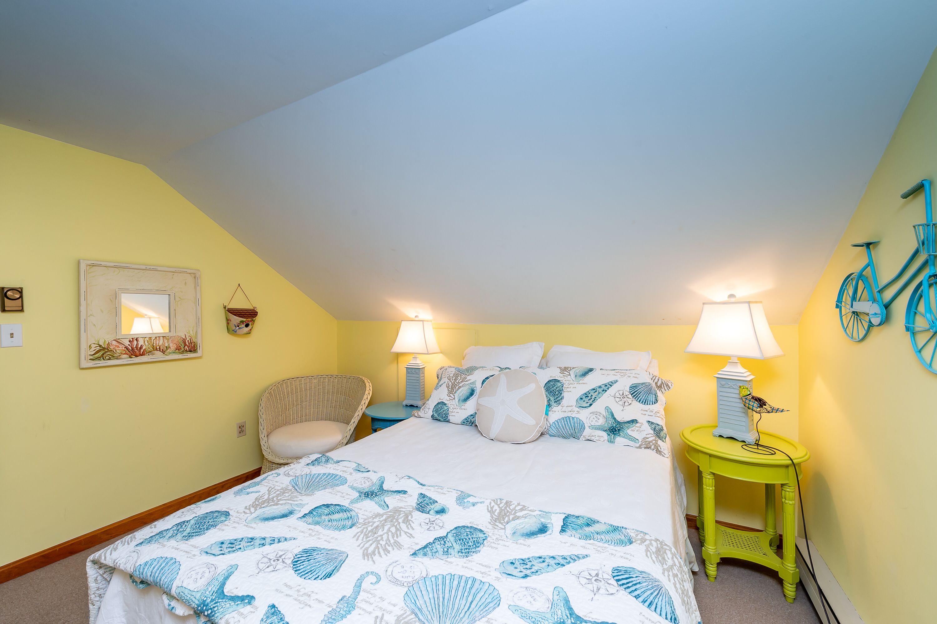 Een slaapkamer met een bed, twee nachtkastjes, een stoel en een fiets als decoratie aan de muur.