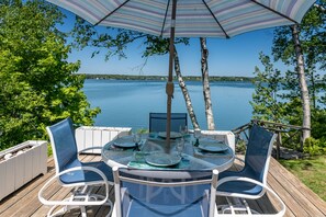A round table with chairs and an umbrella, overlooking a lake.