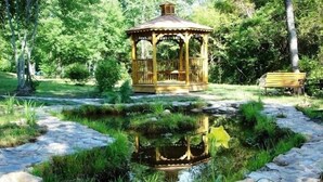 A gazebo with a stone pathway leading to a pond, surrounded by greenery. - Romantic Mountain Chalet with Stream & Gazebo   (Murphy)