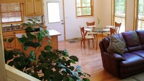A cozy living room with a leather sofa and a dining area with a glass table. - Romantic Mountain Chalet with Stream & Gazebo   (Murphy)