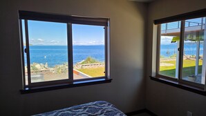 Habitación con cama y dos ventanas que dan a vistas costeras.