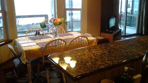 Un comedor con una mesa dispuesta para dos personas, un televisor y vistas al exterior.