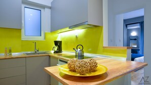 Una cocina moderna con salpicadero amarillo, un hervidor de acero inoxidable y una encimera de madera con un objeto decorativo.