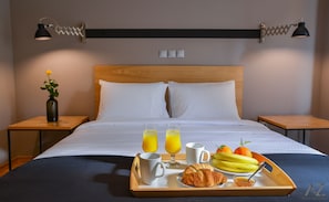 Relax in comfort with a large bed, two nightstands, and a tray offering a selection of fresh fruit and refreshments.