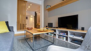 Una sala de estar moderna con un televisor de pantalla plana, una mesa de centro y una estantería.
