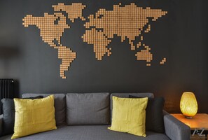 Un canapé gris avec des coussins jaunes et une décoration murale représentant une carte du monde.