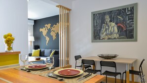 Un comedor con una mesa de madera dispuesta para dos, un mural de un mapa mundial y un cuadro sobre la mesa.