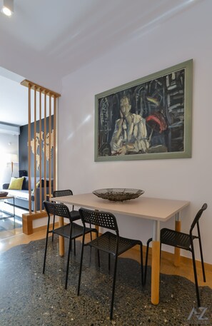 Un espace repas comprenant une table, des chaises, un paravent décoré d’une carte du monde et un tableau accroché au mur.
