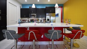 A modern kitchen with dark cabinets, a white countertop, and a red island with bar stools. - EPIC VALUE-Disney Retreat! Magical Kid Friendly! Resort! (Davenport)