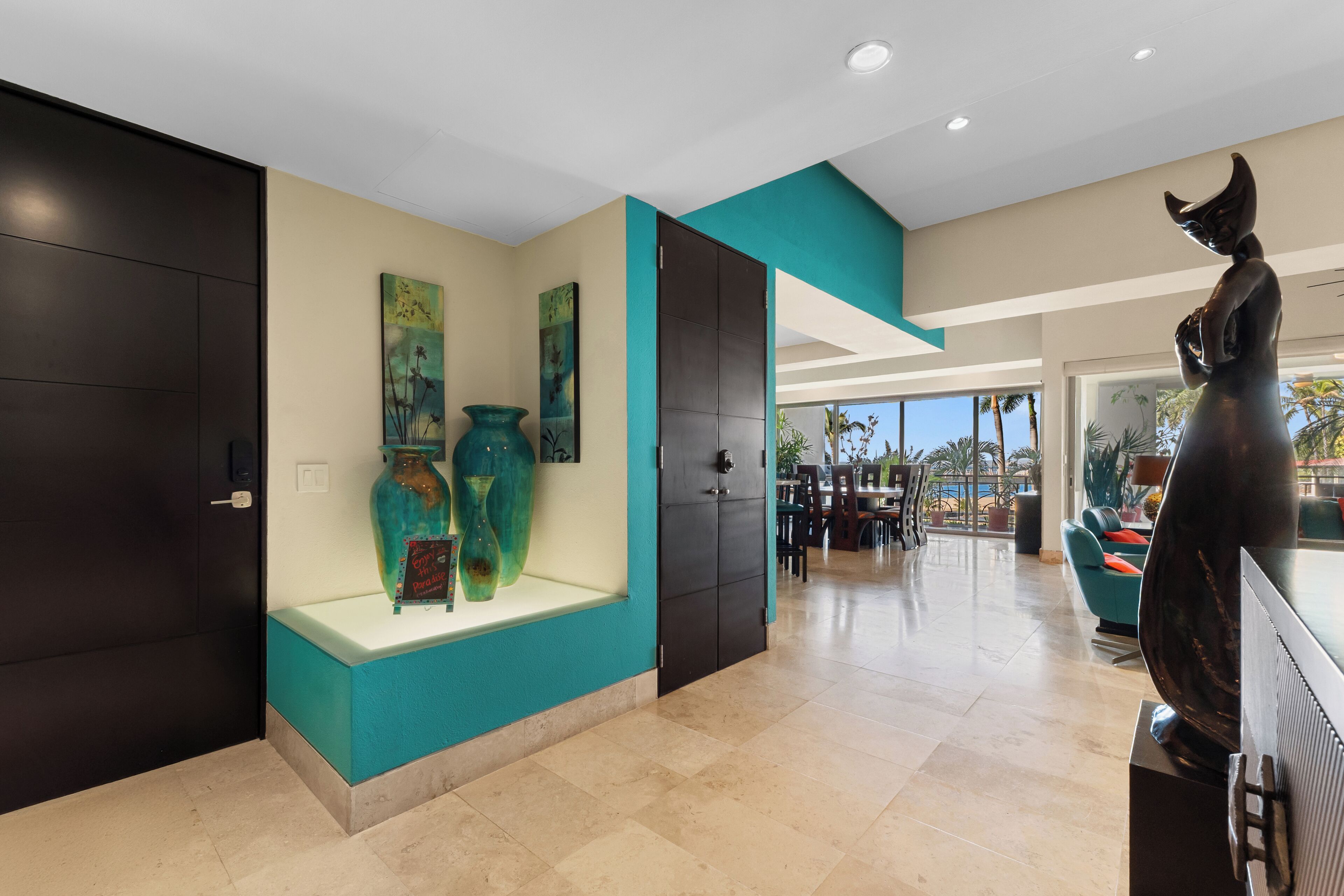A modern interior with teal accents, a display of vases, and a sculpture.