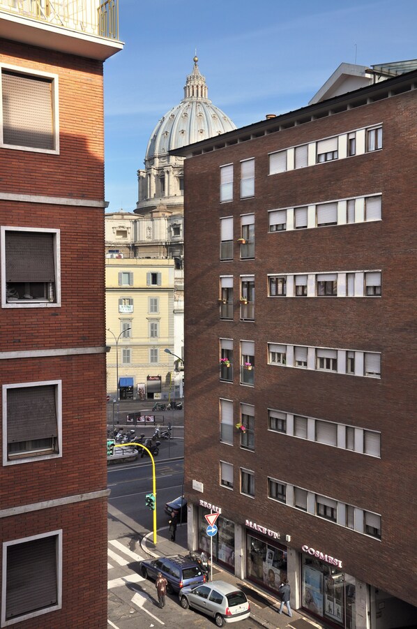 Straßenansicht mit einem markanten rotbacksteingebäude, einer Kuppel im Hintergrund und einem Laden mit einem Schild.
