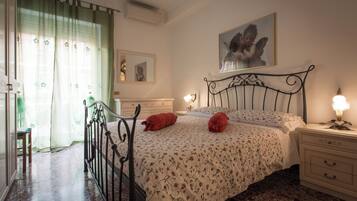A bedroom with a bed, bedside tables, a mirror, and a window with curtains.