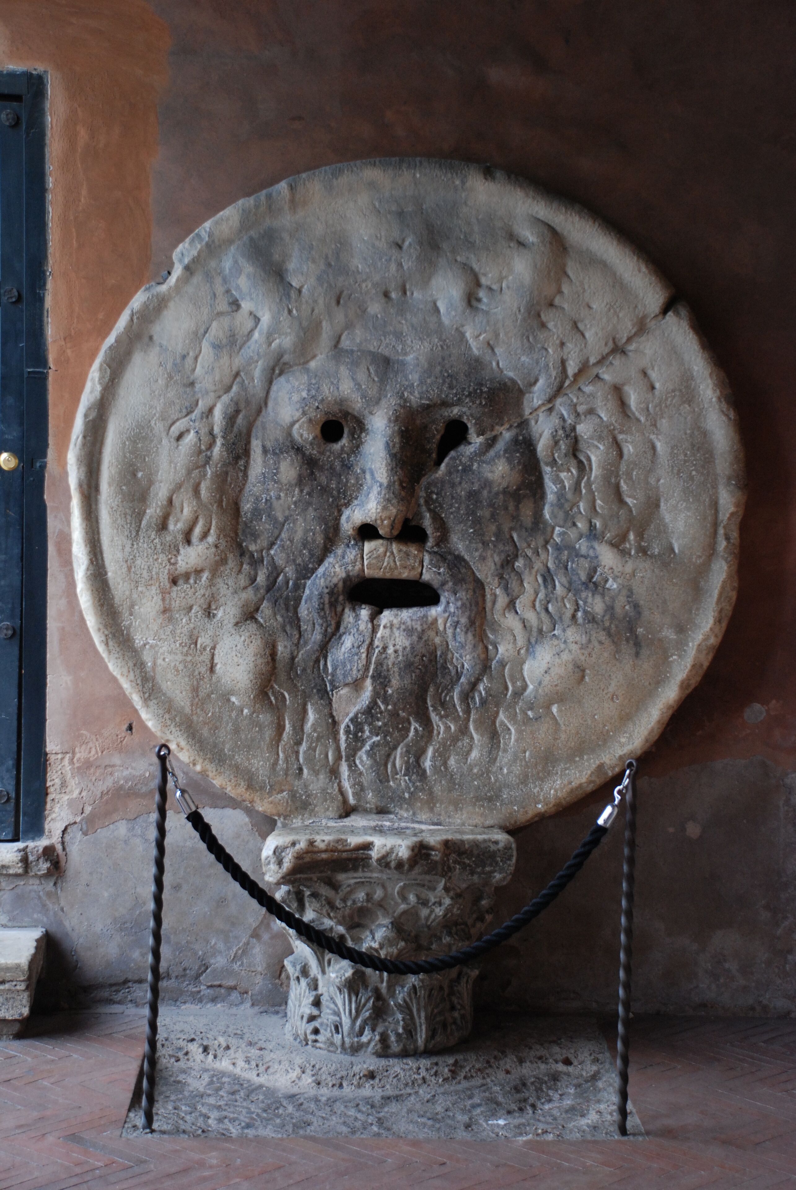 A stone bust with a chain around it, placed on a pedestal.