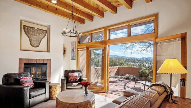 A spacious living room with a fireplace, leather sofas, a round coffee table, and large windows offering a view of the landscape. - Close to Santa Fe Opera, Four Seasons, Pool Access (Santa Fe)