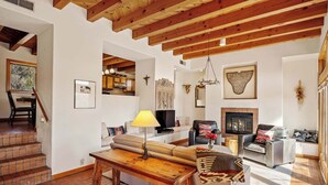 A spacious living area with a wooden ceiling, a fireplace, and a dining area with a table and chairs. - Close to Santa Fe Opera, Four Seasons, Pool Access (Santa Fe)