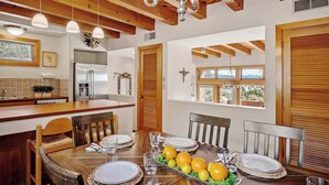 A dining area with a wooden table set for four, a kitchen with modern appliances, and large windows offering a view of the outdoors. - Close to Santa Fe Opera, Four Seasons, Pool Access (Santa Fe)