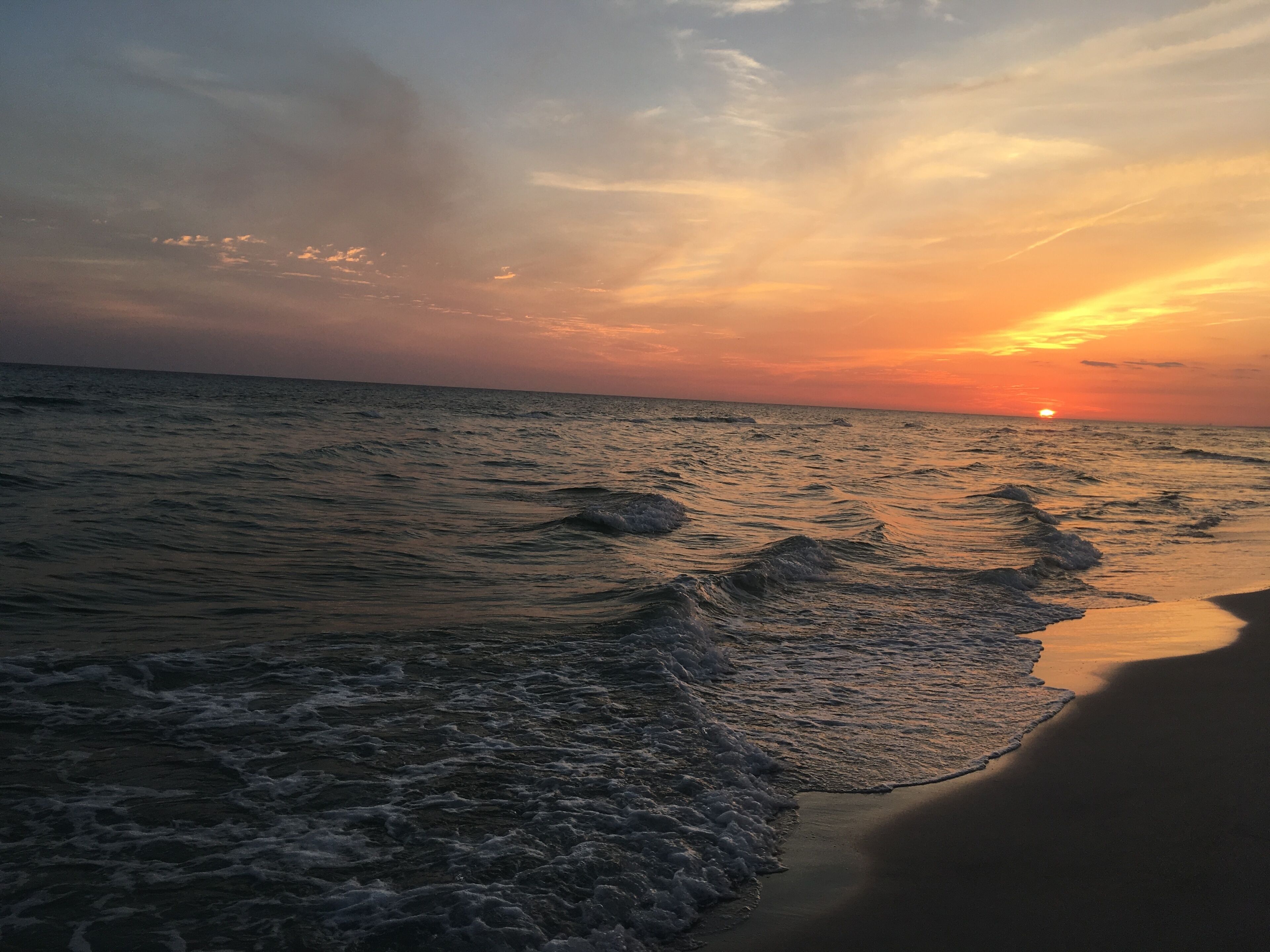 Une plage au coucher du soleil, avec des vagues qui se rapprochent du rivage.