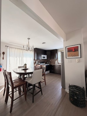 A modern kitchen with dark cabinets, a dining table with chairs, and a chandelier. - Fenced lot,dog friendly, strong WIFI, beach view, fire pit, budget, best memory  (Lower Township)