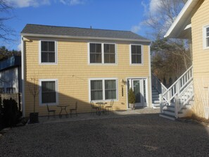 A two-story house with a front porch, a staircase, and a gravel driveway.