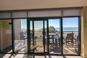 Enjoy the ocean view from this balcony with comfortable seating and a glass door leading to the outdoor space.