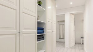 Un couloir avec deux portes blanches, un banc et un miroir accroché au mur.
