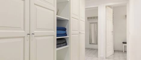 A hallway with white double doors, a bench, and a mirror on the wall.