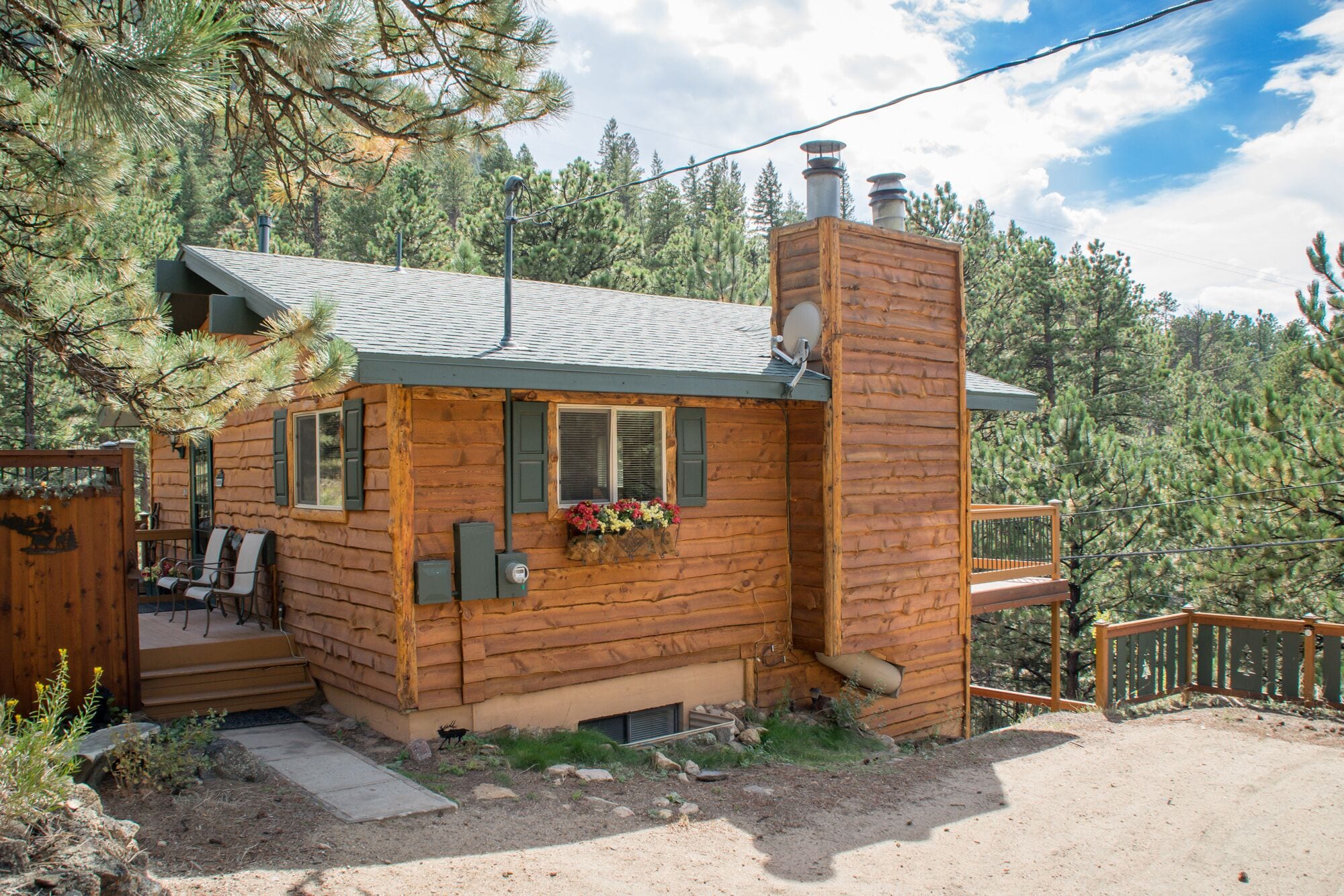 A log cabin with a chimney, a deck, and a small porch.