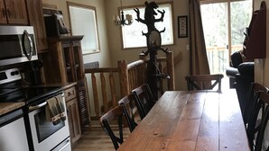 Een ruime keuken met houten kastjes, een grote eettafel en uitzicht op de omgeving.